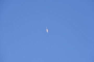 Distant Rocket Launch clear Blue Day with exhaust trail and sunny sky