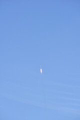 Distant Rocket Launch clear Blue Day with exhaust trail and sunny sky