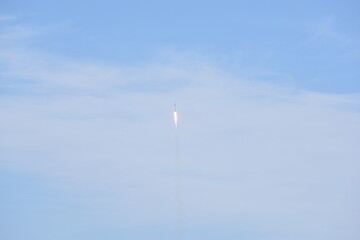 Distant Rocket Launch clear Blue Day with exhaust trail and sunny sky