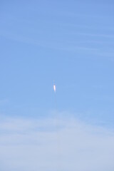 Distant Rocket Launch clear Blue Day with exhaust trail and sunny sky