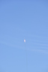 Distant Rocket Launch clear Blue Day with exhaust trail and sunny sky