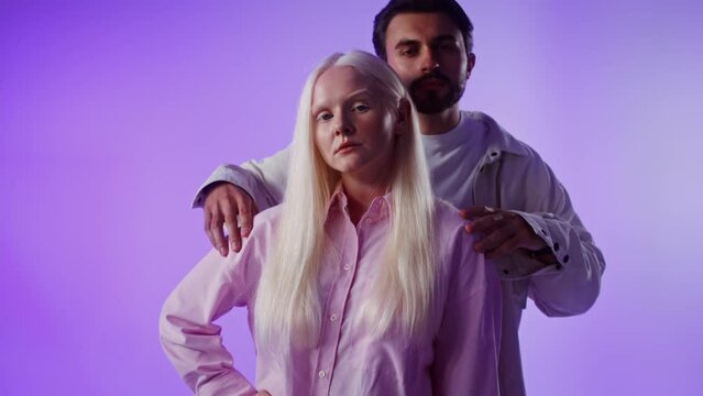 Man peeking out from behind woman posing against monochrome background