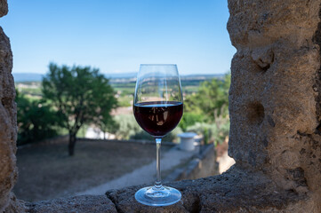 Glass of red dry wine and ruins of medieval castle of Châteauneuf-du-Pape ancient wine making village in France