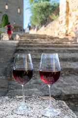 Glass of red dry wine and ruins of medieval castle of Châteauneuf-du-Pape ancient wine making village in France