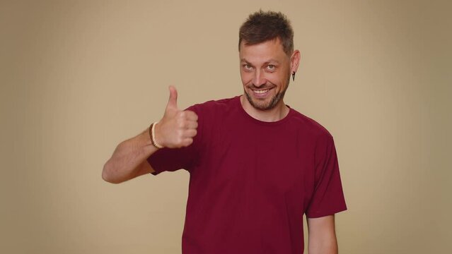 Look at advertisement. Bearded handsome young man pointing down, saying to subscribe, gesturing ok and like, showing place for commercial, promotional information below. Adult guy on beige background