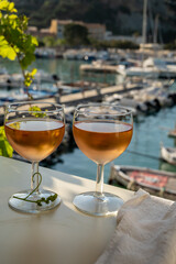 Cold rose wine in glasses served on outdoor terrace in sunlights with view on old fisherman's...