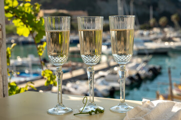 Three glasses of French champagne sparkling wine and view on colorful fisherman's boats in old harbour in Cassis, Provence, France
