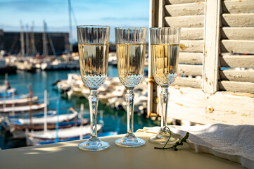 Three glasses of French champagne sparkling wine and view on colorful fisherman's boats in old...