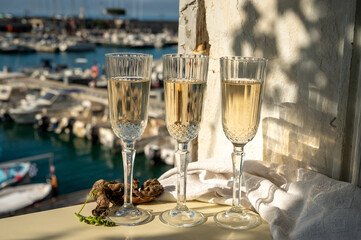 Three glasses of French champagne sparkling wine and view on colorful fisherman's boats in old harbour in Cassis, Provence, France