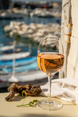 Cold rose wine in glass served on outdoor terrace in sunlights with view on old fisherman's harbour...
