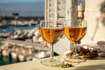 Summer party with cold rose wine in glass served on outdoor terrace in sunlights with view on old...