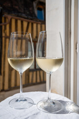 Tasting of white grand cru classe chablis wine with old French houses on background, Burgundy, France