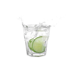 Water with sliced lime splashing out of glass on white background