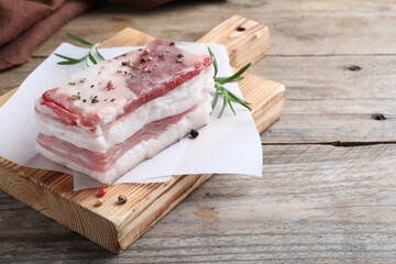 Tasty salt pork with rosemary and spices on wooden table, space for text