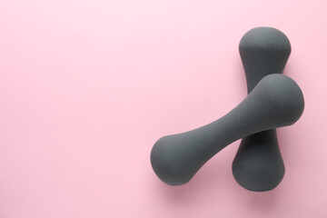 Grey dumbbells on light pink background, top view. Space for text