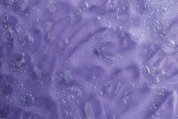 Texture of transparent shower gel on violet background, closeup