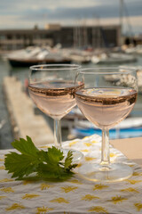 Rose wine in glasses served on outdoor terrace with view on old fisherman's harbour with colourful boats in Cassis, Provence, France