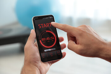 Man using fitness app on smartphone indoors, closeup