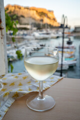 Cold white wine from Cassis region served in glass on outdoor terrace with view on old fisherman's harbour with colourful boats in Cassis, Provence, France