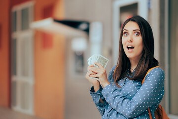 Cheerful Woman Holding Cash Money in front of an ATM Machine. Happy person winning extra dollars...