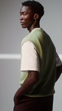 A man in a knitted vest turns seriously looking at the camera, vertical video