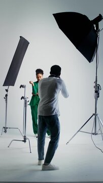 Photographer and model work in studio, vertical video