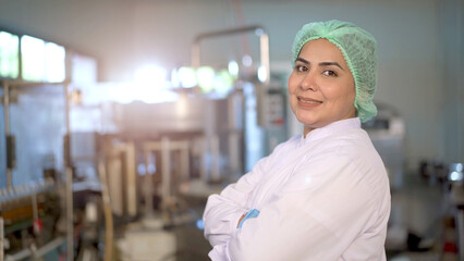Happy Asian female portrait in manufacturing factory smiling - arm crossing and looking at the...
