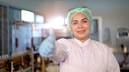 Happy Asian female portrait in manufacturing factory smiling - arm crossing and looking at the camera. 