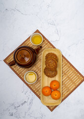 3 Moon Cakes and 3 tangerines on a tray, served with Chinese tea