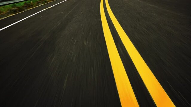 Front pov view of fast car driving on asphalt road with double yellow lines converge
