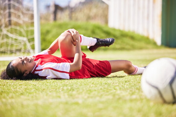 Injured, pain or injury of a female soccer player lying on a field holding her knee during a match....