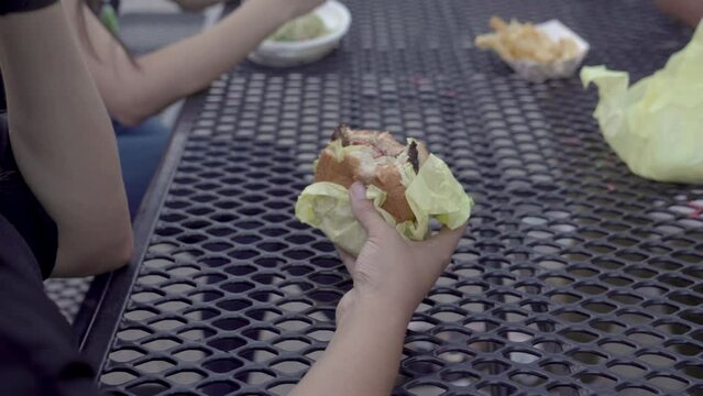 Very close up frame of a Native teacher eating a burger during lunch time.