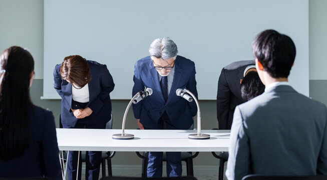 会見で謝罪をするビジネスピープル