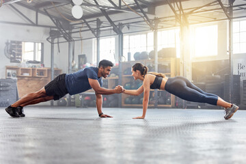 Active couple holding hands for support in pushup, plank and balance training during fitness,...
