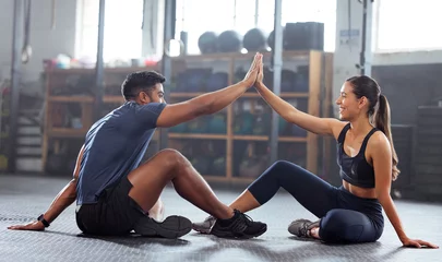 Tuinposter Motivation, celebrate and support with fitness coach doing high five with woman in the gym. Active and fit woman training or practicing strength and stamina workout with her friend in a health center © Alex S/peopleimages.com