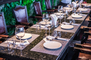 A long table is filled with all kinds of tableware, including glasses, cutlery, plates, paper...