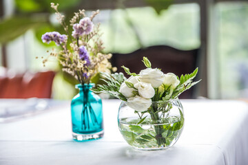 Vase with purple and white flowers on table