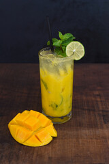 Mango mojito in highball glass with sliced mango isolated on wooden table