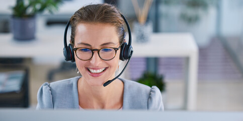Happy, smiling and friendly call center agent or telemarketing operator wearing headset while working in an office. Smile of a sales consultant operating helpdesk for customer and service support - obrazy, fototapety, plakaty