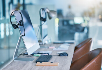 Headphone or headset in an empty call center office with computer monitor display for online customer service or support. Helpdesk hotline assistance gadgets and crm equipment in workplace or station - Powered by Adobe