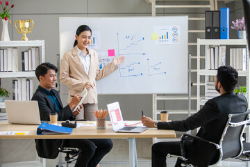Asian business team male and female colleagues talking at work share ideas with chart on board, Happy young presenttation colleagues work together on board.