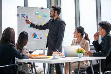 Asian business team male and female colleagues talking at work share ideas with chart on board, Happy young presentation colleagues work together on board.