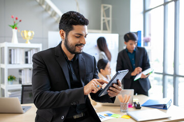 Portrait of Asian businessman working at the office, smart businessman using touchpad with smile at working place.