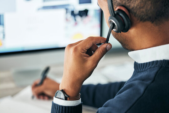 Call center, customer service and agent assisting online customer with a headset and taking notes. Closeup of a male financial consultant or telemarketer working on a computer to consult clients. - Powered by Adobe