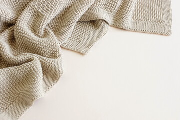Beige knitted blanket on beige  background with copy space.Autumn, winter  template.Flat lay, top view