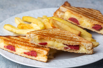 Turkish toast, mixed toast with cheddar cheese, sausage and ham, with fried potatoes (Turkish name; Karisik tost)