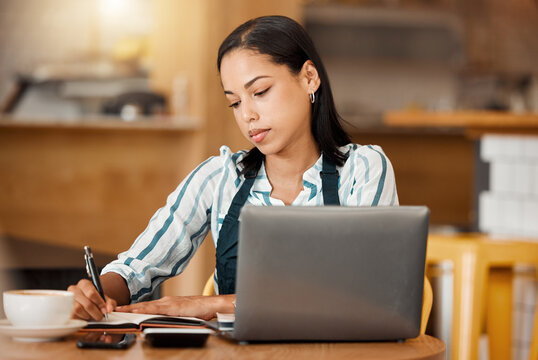 Cafe Owner, Coffee Shop Manager Or Small Business Entrepreneur Writing Notes And Working On A Laptop In Her Startup. Young Female Looking Serious While Managing Finance And Capital Of Her Bistro