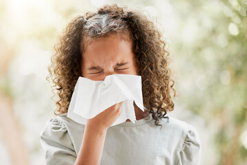 Sick little girl with a flu, blowing her nose and looking uncomfortable. Child suffering with...