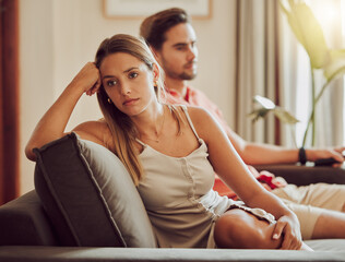 Unhappy, sad and annoyed couple after a fight and are angry at each other while sitting on a couch...