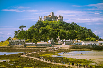 Picturesque view of St Michael's Mount in Cornwall, England, at low tide on nice day with small...